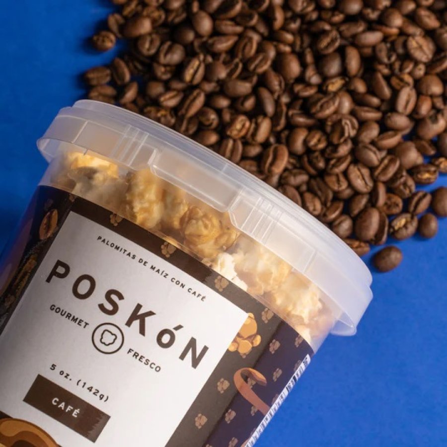 Overhead shot of a package of Poskon Puerto Rican popcorn laid on its side with coffee beans scattered around.