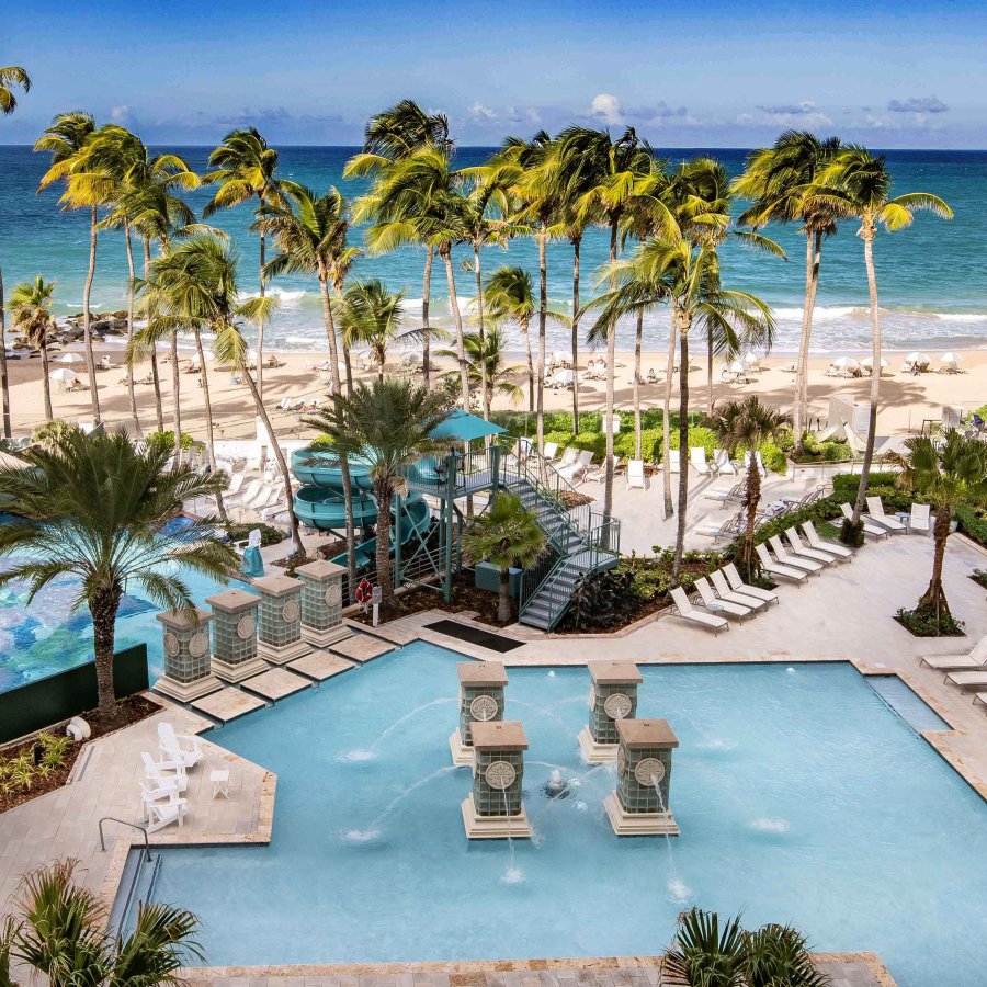 Multiple swimming pools, flanked by palm trees, are pictured with the ocean in the background at the San Juan Marriott Resort & Stellaris Casino. San Juan, Puerto Rico.