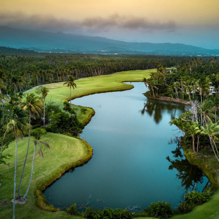 Aerial view of the lush golf course at St. Regis Bahia Beach Resort & Golf Club, with El Yunque in the background.