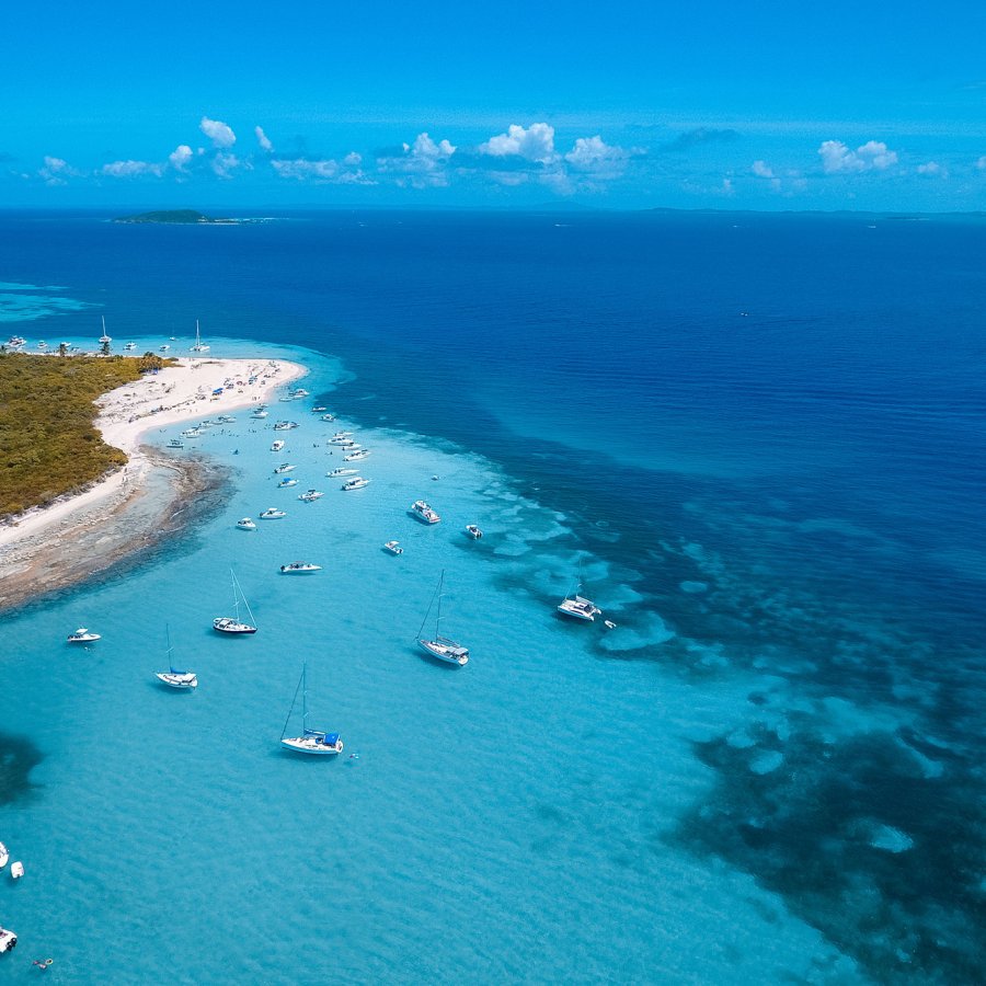 Vista aérea de la costa de Cayo Icacos en la costa este de Puerto Rico, con agua azul clara y varios barcos anclados cerca de la orilla.