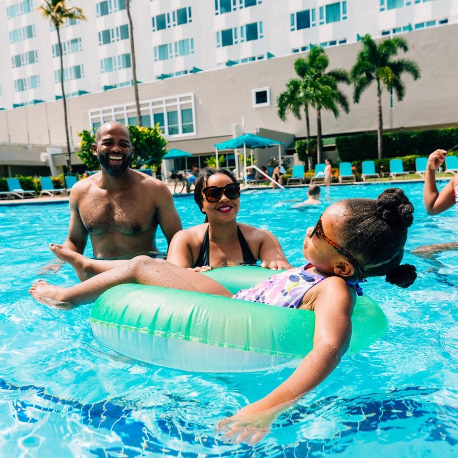 A family with two parents and two kids plays in a resort pool in Puerto Rico.