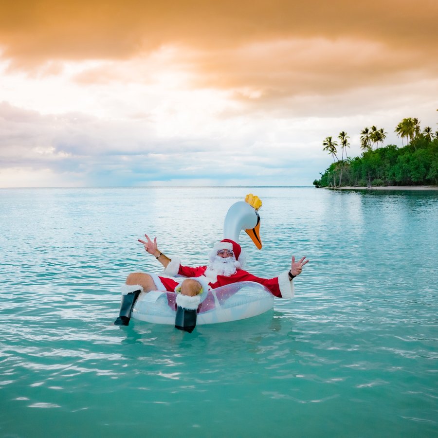 santa claus floats around a beach. 