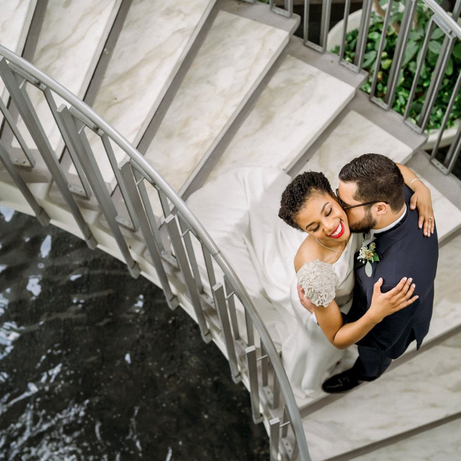 Overhead wedding photo of a couple embracing on a spiral staircase over water at La Concha Renaissance Resort. San Juan, Puerto Rico.