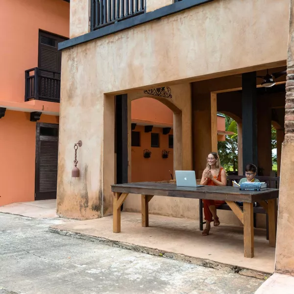 A woman and young boy sit at a desk overlooking a historic street in Puerto Rico.