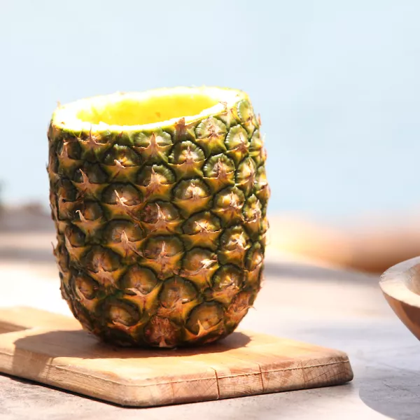 A pineapple is halved, cored and filled with blended juice.