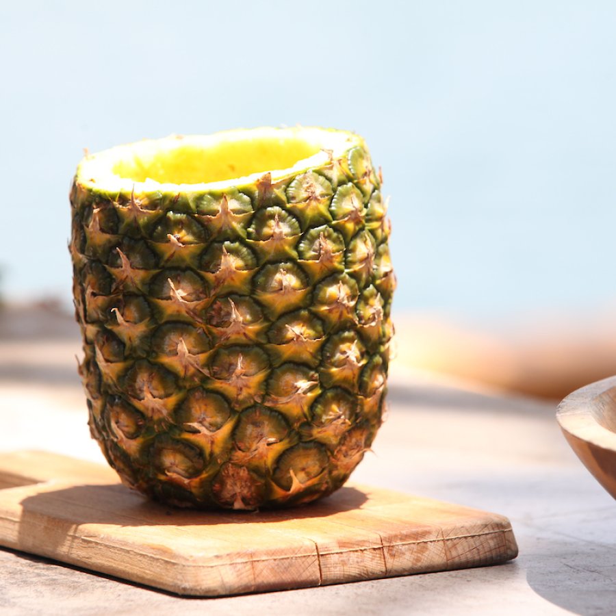 A pineapple is halved, cored and filled with blended juice.