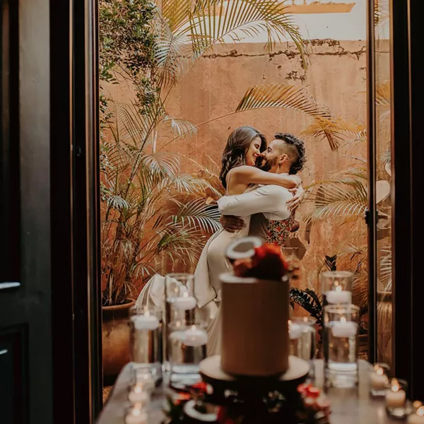 A couple embraces on a balcony at Hotel El Convento with a wedding cake in the foreground — a romantic venue for Puerto Rico wedding packages.