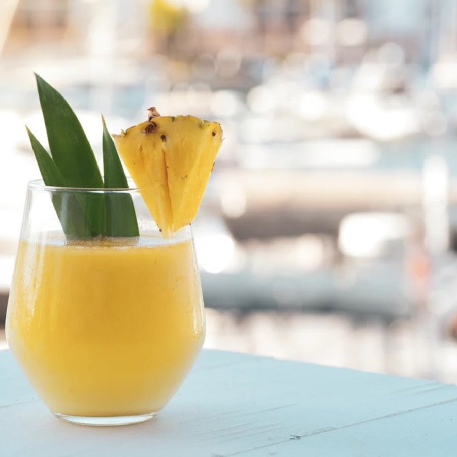 A glass filled with fresh juice and a pineapple slice on the rim.