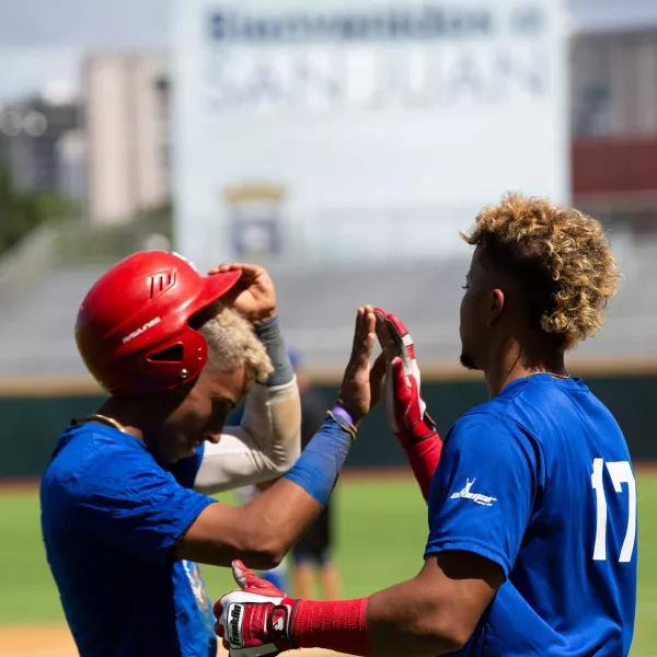 Two baseball players high five after a game in Puerto Rico.