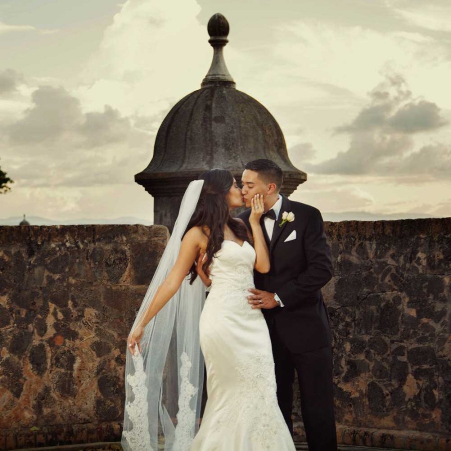 A bride and groom kiss in front of a historic garita in Old San Juan. Photo by Noel Del Pilar.
