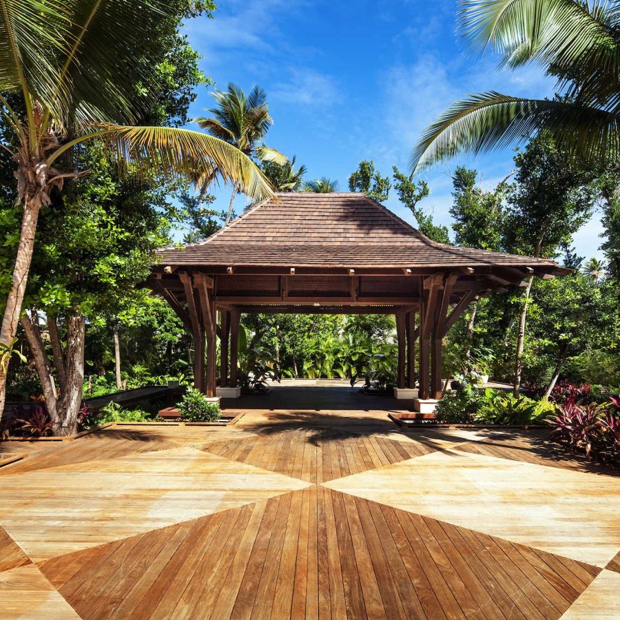 A wooden porte-cochere is surrounded by palm trees and lush greenery at St. Regis Bahia Beach Resort, Puerto Rico