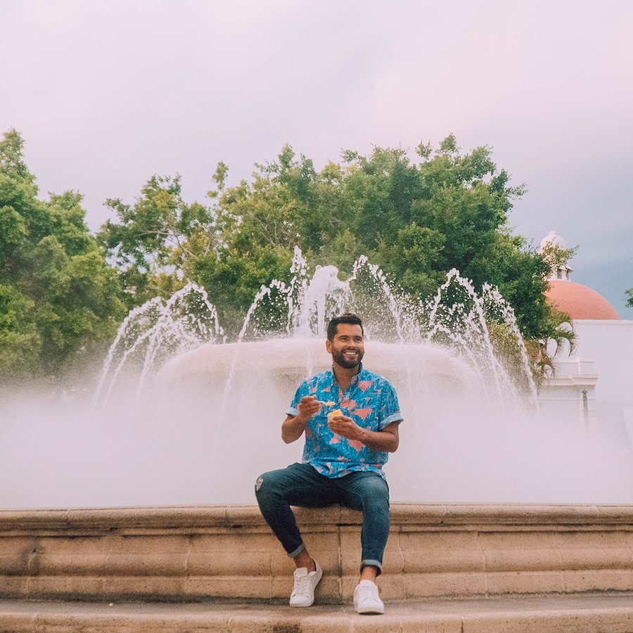 Man enjoying his ice cream while sitting on the ledge of a large fountain in downtown Ponce.
