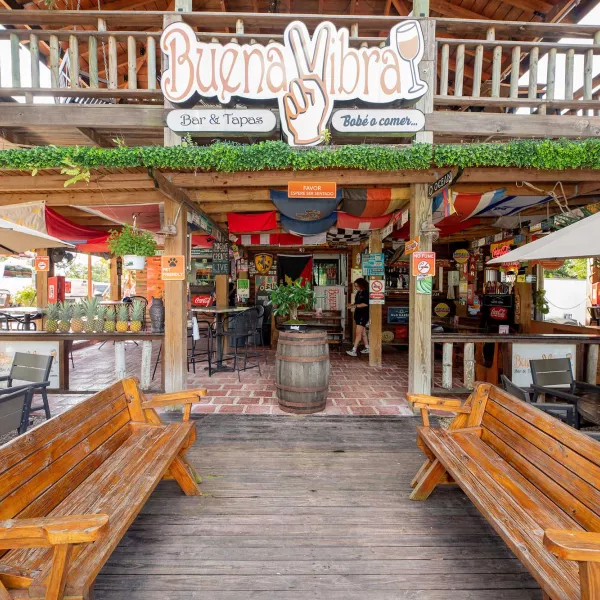 Exterior of a two-story beach bar and restaurant in Cabo Rojo, Puerto Rico, with two wooden benches sitting in the front.