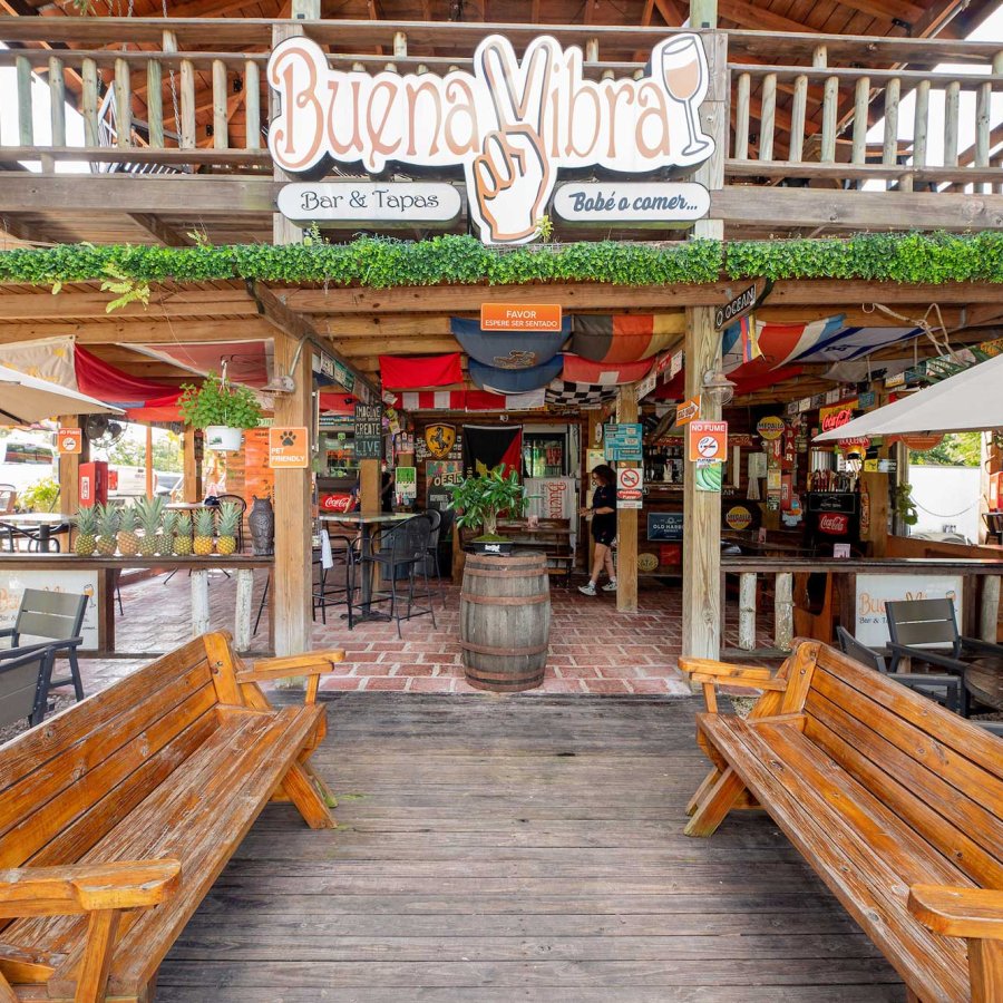 Exterior of a two-story beach bar and restaurant in Cabo Rojo, Puerto Rico, with two wooden benches sitting in the front.