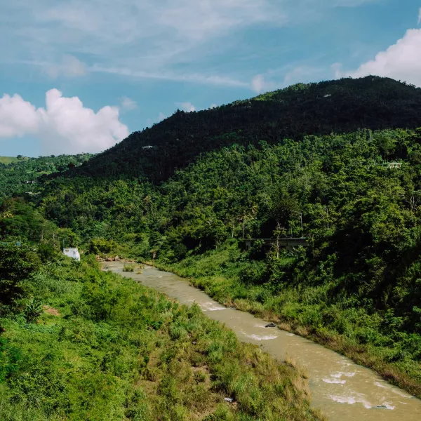 A river runs through a hilly, green countryside in Comerío, Puerto Rico.