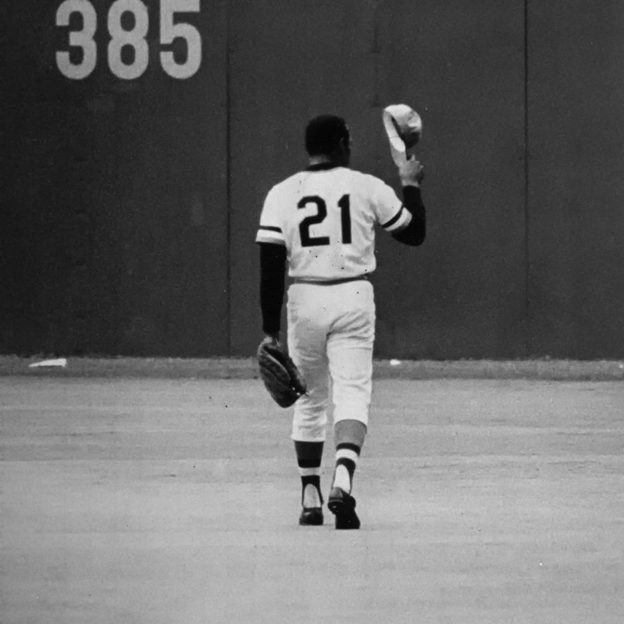 Roberto Clemente in the baseball field with a hat off.