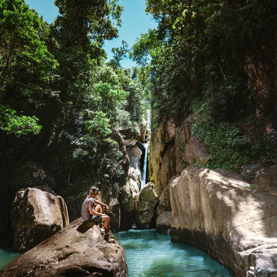 Hiker standing in front of a waterfall in El Yunque National Forest, Puerto Rico rainforest adventure.
