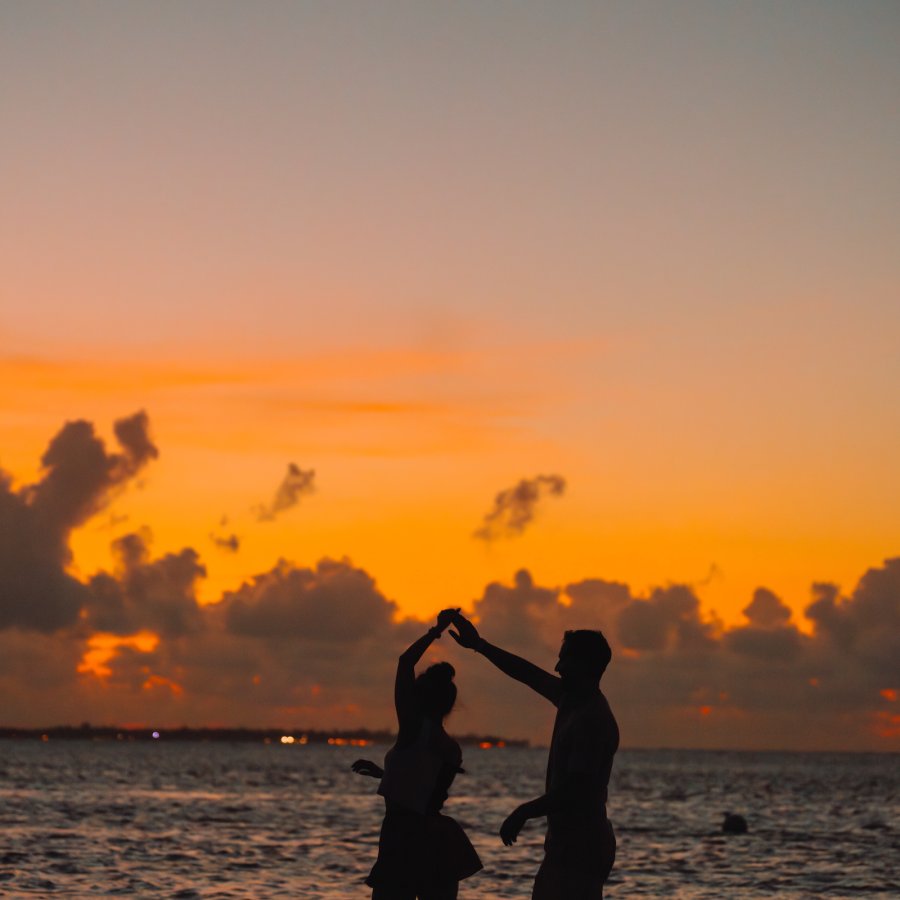 Couple dancing on the beach at sunset.