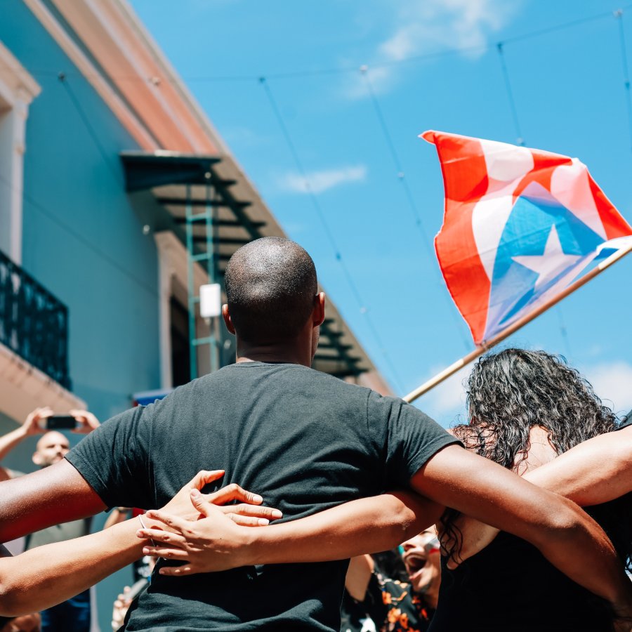 People hug with the Puerto Rican flag