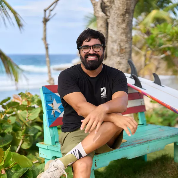 Héctor Varela, Program Manager at Surfrider, seated in front of the beach.