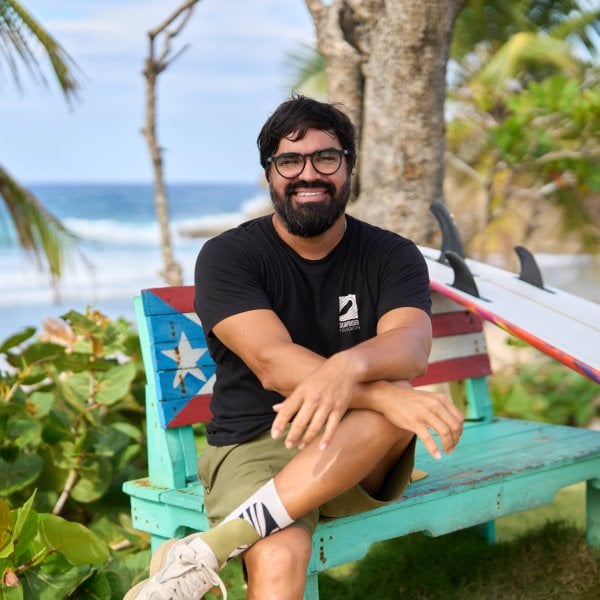Héctor Varela, Program Manager at Surfrider, seated in front of the beach.