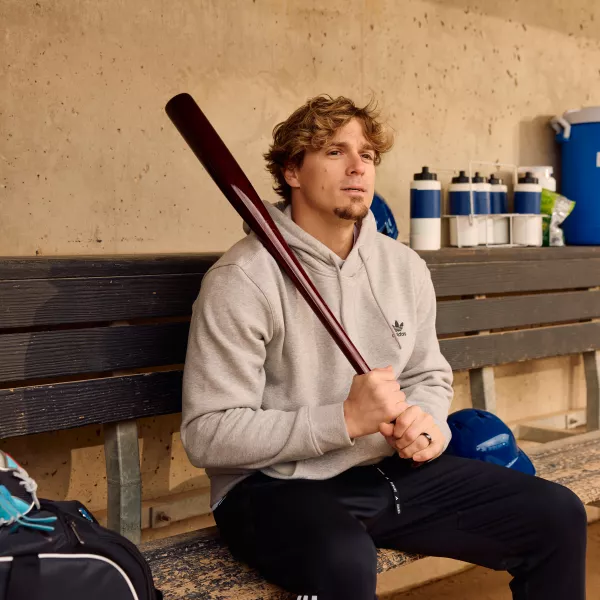 Kike Hernandez holds a bat in a baseball dugout. 