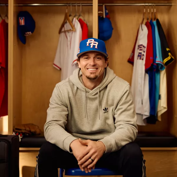 Baseball player Kike Hernandez sits in a locker room with Puerto Rico's basbeball hat. 