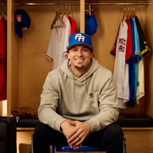 Baseball player Kike Hernandez sits in a locker room with Puerto Rico's basbeball hat. 