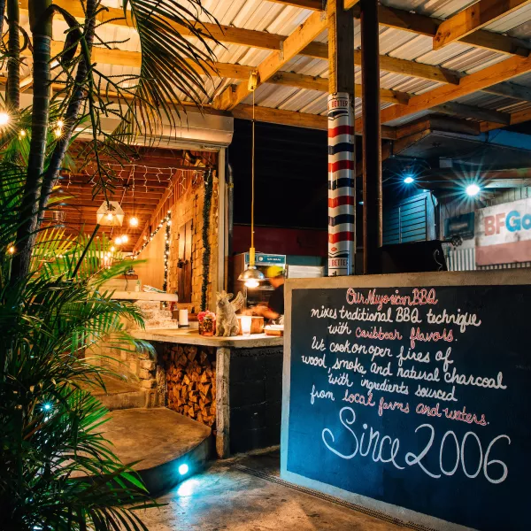 Outdoor dining area of La Estación BBQ restaurant in Fajardo, Puerto Rico, with a chalkboard menu and warm ambient lighting.