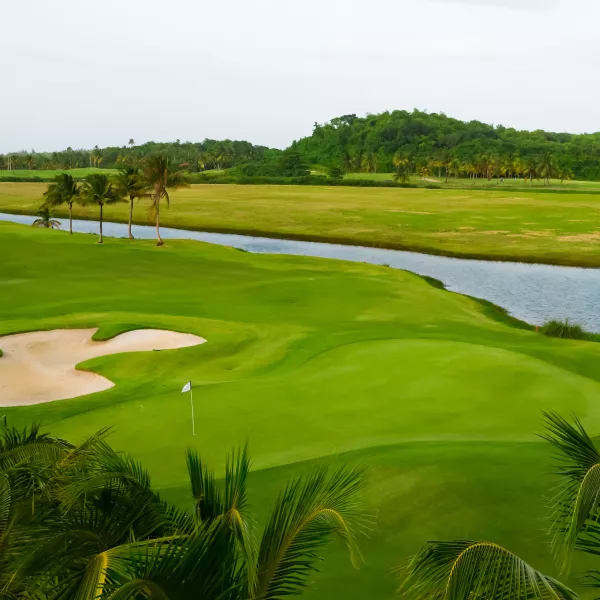 view of the Grand Reserve Golf Club in Puerto Rico, featuring lush fairways, sand bunkers, and water features surrounded by tropical landscape.