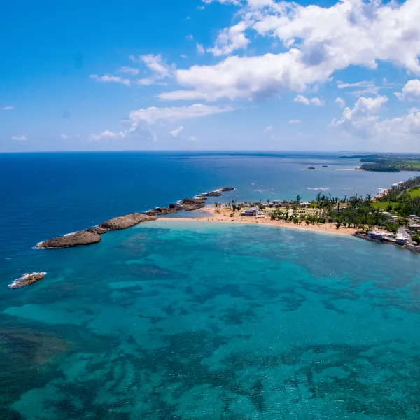 A view of Puerto Nuevo Beach in Vega Baja, Puerto Rico, showing golden sand, turquoise waters, and natural rock formations protecting the sho