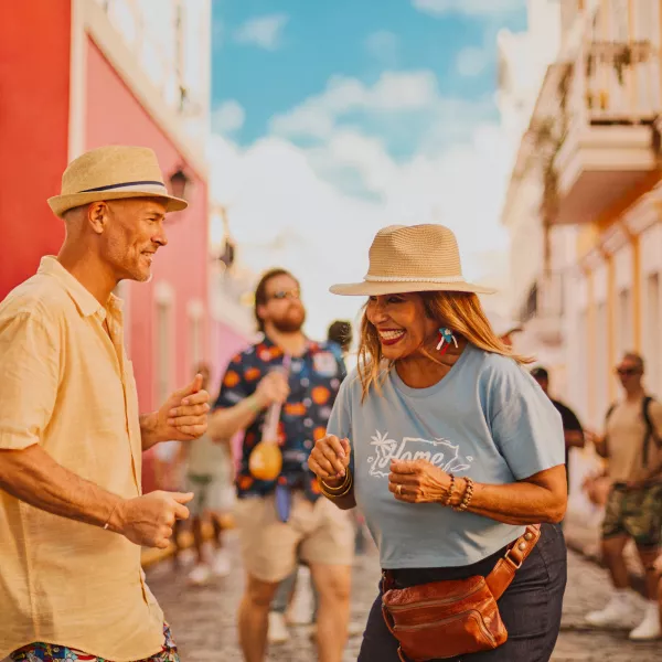 People smiling and dancing on a colorful street in Old San Juan.