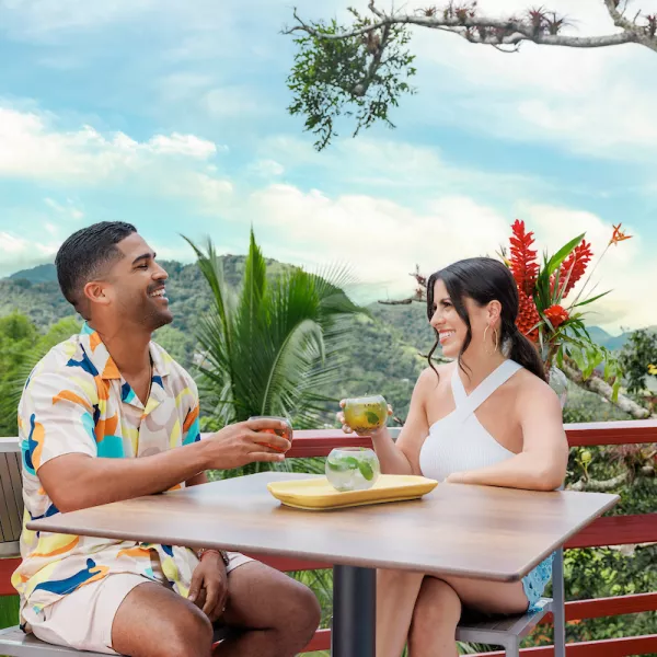 Couple enjoying tropical cocktails on an outdoor terrace overlooking the lush mountains in Cayey.
