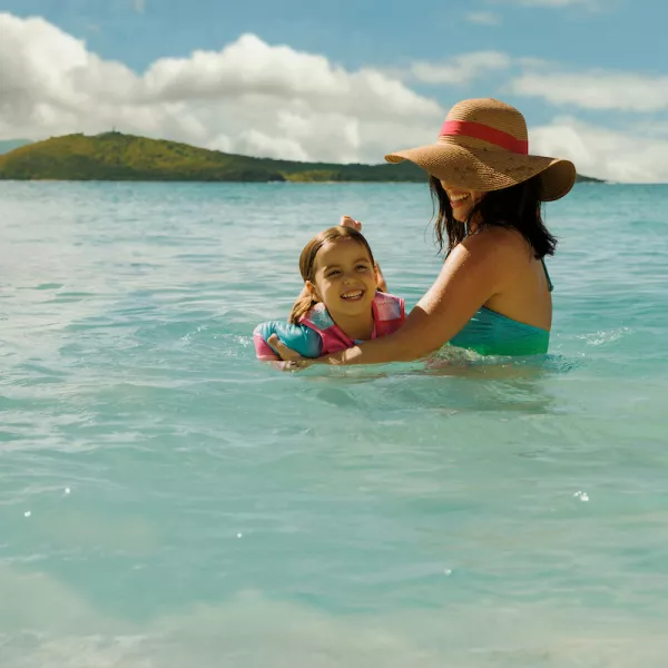 Mother and daughter enjoying the calm turquoise waters at a beach on Puerto Rico’s east coast, with small islands visible in the distance.