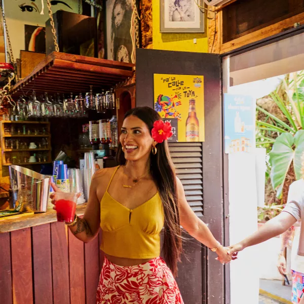 Two women entering a colorful bar in Old San Juan, holding hands and drinks