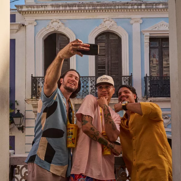Three friends taking a selfie in front of a colorful historic building in Old San Juan during golden hour.