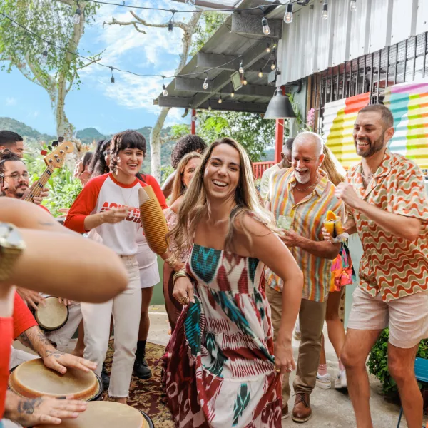 People dancing and playing percussion together at an outdoor gathering in Puerto Rico, surrounded by colorful buildings and live music.