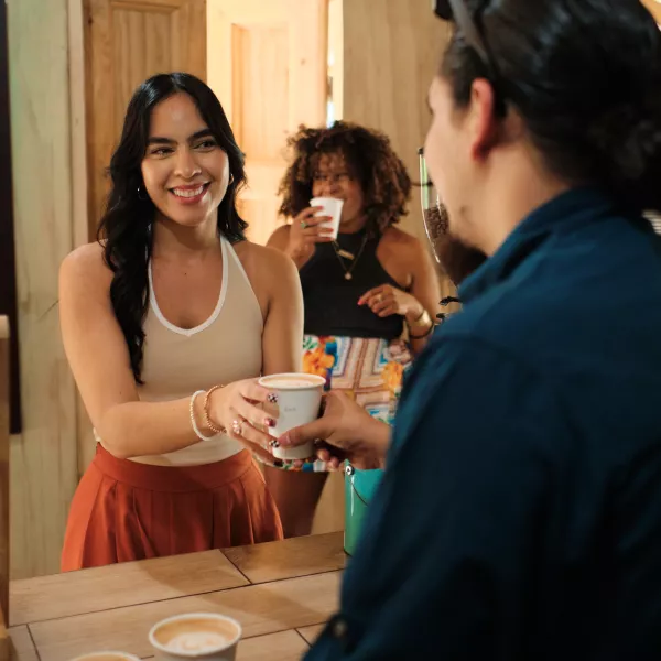 A woman receiving her cup of coffee at a rustic alike coffee shop.