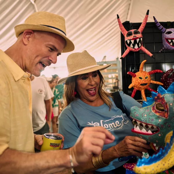 Visitors browse colorful handcrafted vejigante masks and artisan creations at a cultural market in Puerto Rico, celebrating the Island’s rich artistic traditions and craftsmanship.