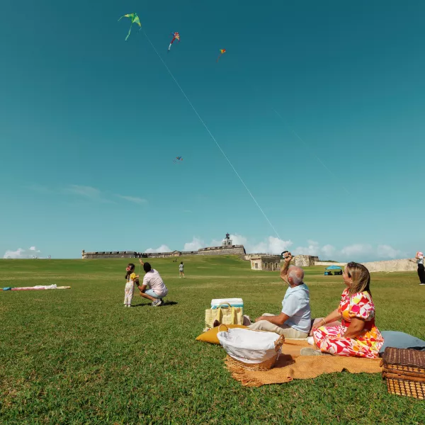 Multi-generational family enjoying a picnic and flying kites at El Morro in Old San Juan.