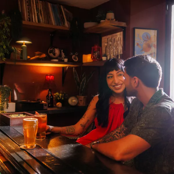 Two people sharing drinks and conversation at a bar in Puerto Rico with a warm, intimate atmosphere.