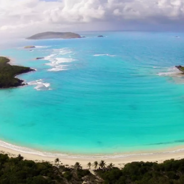 Aerial view of Playa Tortuga on Isla Culebrita, featuring white-sand shores, turquoise water, and a crescent-shaped bay surrounded by coastal vegetation.