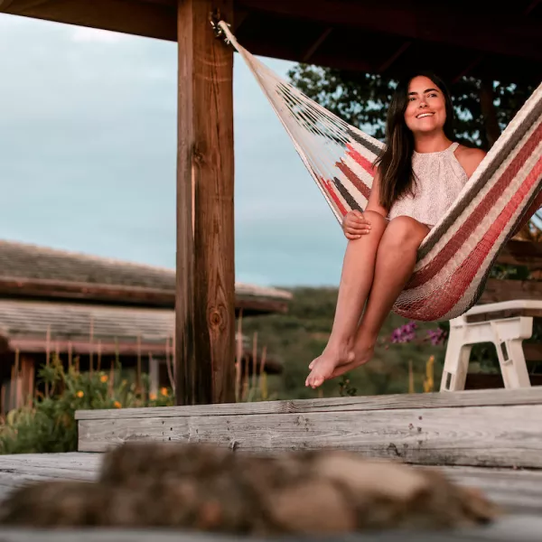 A woman relaxes in a hammock on a wooden deck in Culebra, Puerto Rico, surrounded by tropical greenery and rustic architecture.