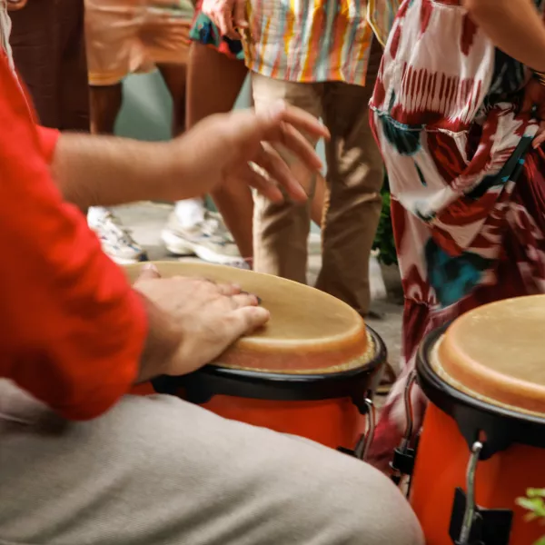 Close-up of musicians playing hand drums while people dance and gather during a lively cultural event, reflecting the music and social atmosphere often found in La Placita de Santurce.