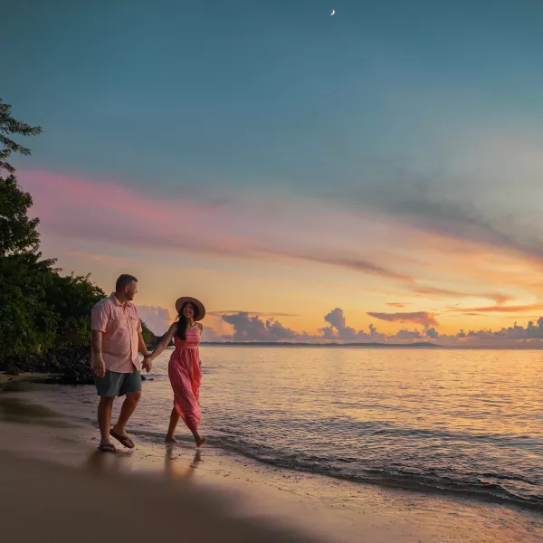 Travelers walking along a quiet beach at sunset in Puerto Rico, enjoying the coastline, warm weather, and natural beauty beyond the resort.