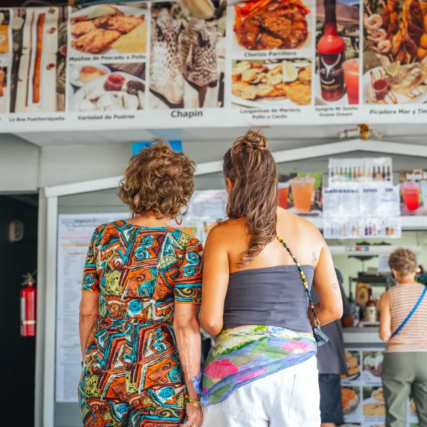 Sabor del Pueblo hosts study a colorful menu filled with Puerto Rican seafood and fritters in Guayama.