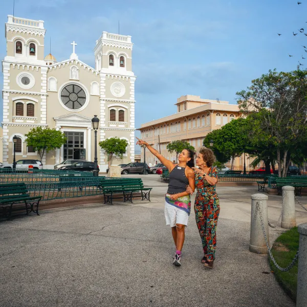 Sabor del Pueblo hosts walk through a historic plaza beside a church in Guayama, southern Puerto Rico.