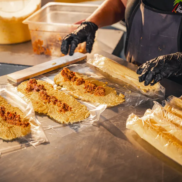 A cook prepares long Puerto Rican fritters by hand on a stainless-steel counter at a restaurant in Guayama.
