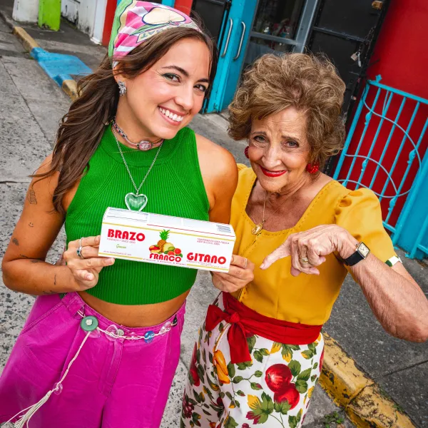 Sabor del Pueblo hosts smile outside in Mayagüez while holding a box of Franco Brazo Gitano.