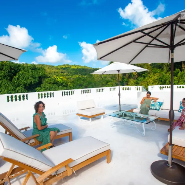 Guests relax on an outdoor terrace at Casa Alternavida in Río Grande, Puerto Rico, with lush green hills in the background.